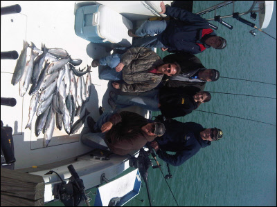 group of 6 on a boat with the fish they caught on Lake Michigan