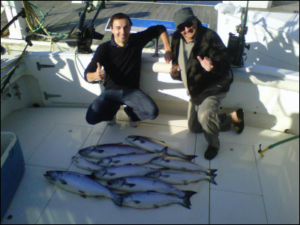 2 guys smiling on boat with their catch
