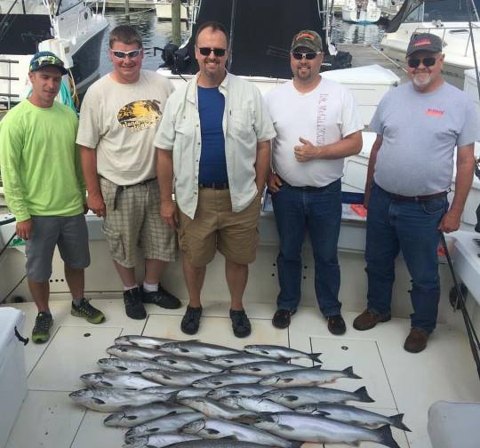 A group of Milwaukee, Wisconsin friends smile with fifteen or twenty fish caught on their Lake Michigan charter fishing trip with Reel Sensations.