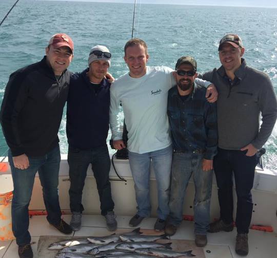A group of fishermen smile with their catch after a successful fishing trip with Milwaukee-area fishing charter company Reel Sensations.